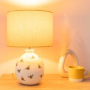 Picture of Bumble Bee Table Lamp with White Ceramic Base And Yellow Lampshade Creating  Warm Living Room Glow